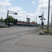 View looking south toward crossing gates and a gas station