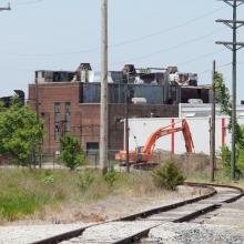 Track with white ballast and orange backhoe in background.